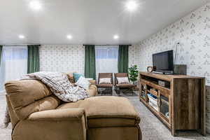 Living area featuring carpet floors, a textured ceiling, and wallpapered walls