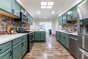 Kitchen featuring green cabinetry, appliances with stainless steel finishes, light countertops, tasteful backsplash, and recessed lighting
