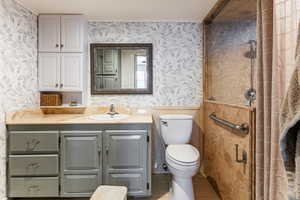 Bathroom with wallpapered walls, vanity, and light tile patterned flooring