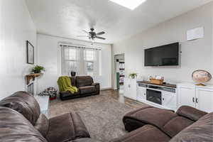 Living area with a textured ceiling, ceiling fan, and wood finished floors