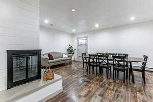Dining space featuring a glass covered fireplace, dark wood finished floors, and recessed lighting