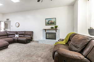Living area featuring carpet, a high end fireplace, and a ceiling fan