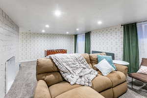 Carpeted living area featuring a textured ceiling, a fireplace, and recessed lighting