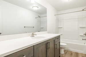 Full bath with vanity, washtub / shower combination, and light wood-style flooring