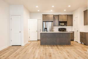 Kitchen featuring black appliances, an island with sink, recessed lighting, light wood-style flooring, and dark brown cabinetry