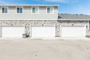 View of garage entry with stucco and stone siding