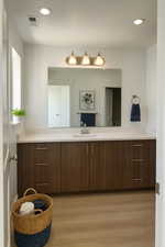 Bathroom with vanity, light wood finished floors, a textured ceiling, and recessed lighting