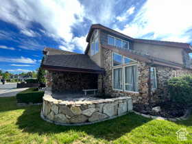 Back of house featuring stone siding, a lawn, and a patio