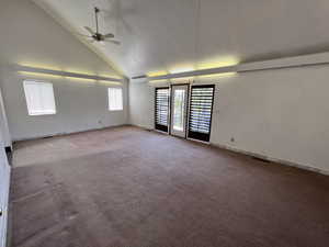 Carpeted spare room with high vaulted ceiling and ceiling fan