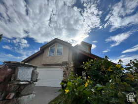 View of front of house with driveway and stone siding