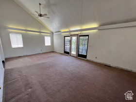 Empty room featuring high vaulted ceiling, dark carpet, and a ceiling fan