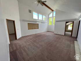 Unfurnished living room featuring beam ceiling, carpet, high vaulted ceiling, and a ceiling fan