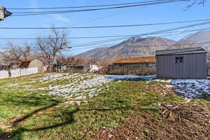 Yard covered in snow featuring a shed and a mountain view