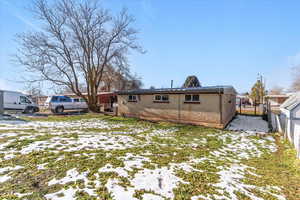 Snow covered back of property featuring brick siding
