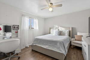 Bedroom featuring dark wood-style floors, ceiling fan, and a desk