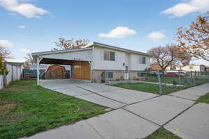 View of front of home featuring brick siding, driveway, a fenced front yard, and a carport