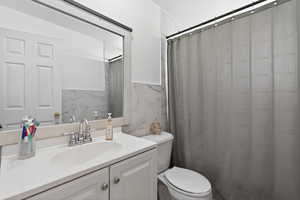 Bathroom with tile walls, vanity, a shower with shower curtain, and a wainscoted wall