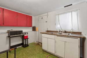 Kitchen with stainless steel microwave, red cabinetry, and a textured ceiling