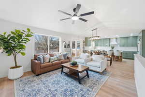 Living area with light wood-style floors, a ceiling fan, and lofted ceiling