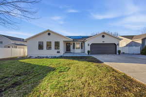 Ranch-style home featuring stucco siding, solar panels, concrete driveway, and a garage