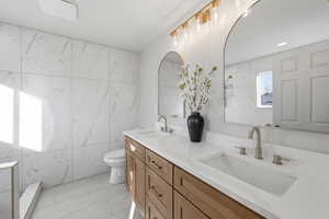 Bathroom with double vanity, tile walls, and light tile patterned floors
