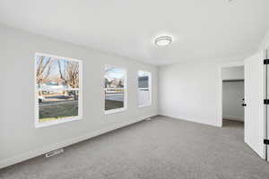 Unfurnished bedroom featuring light colored carpet and a spacious closet