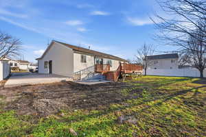 Rear view of house featuring stucco siding, stairs, and a wooden deck