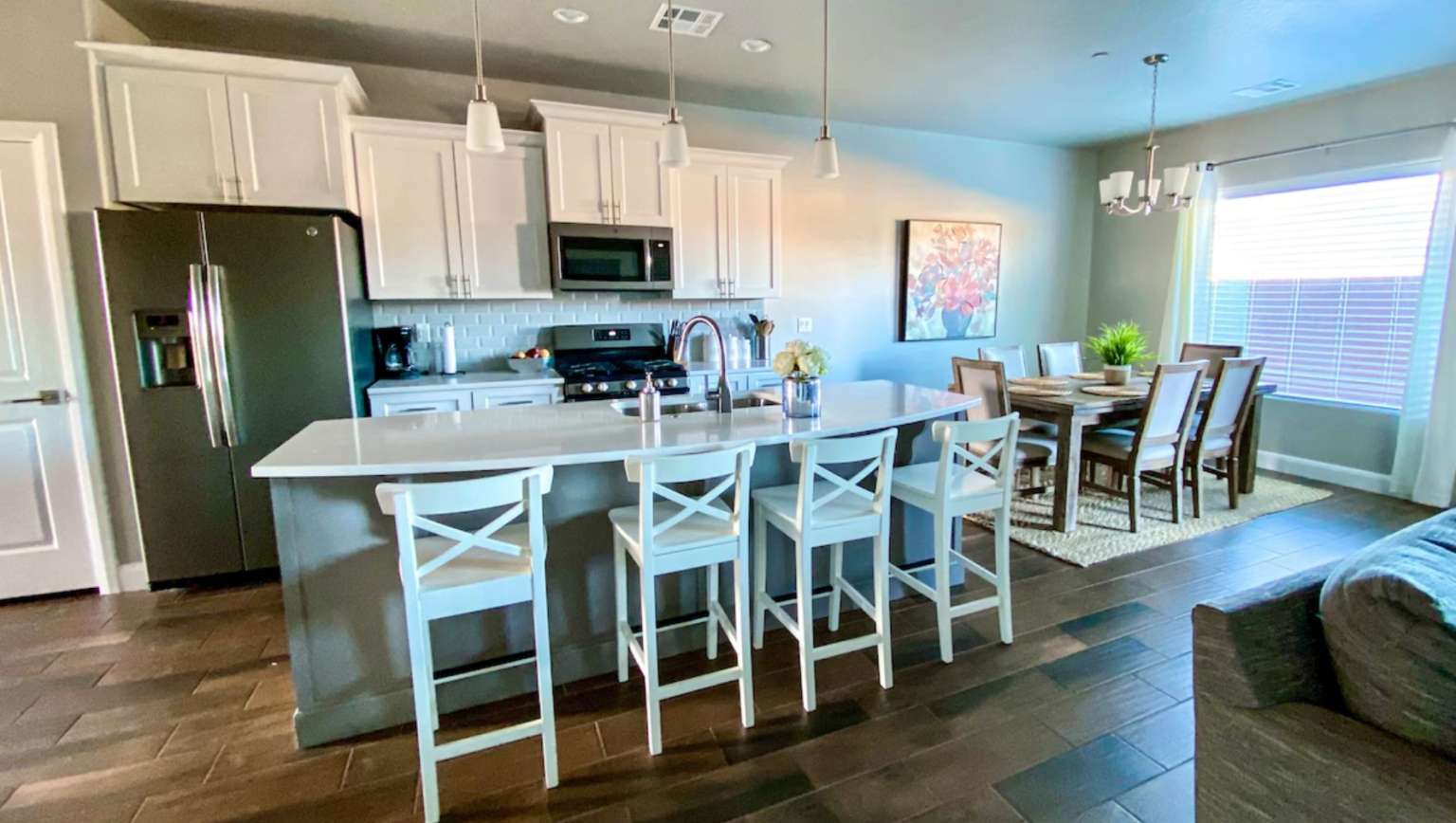 Kitchen featuring appliances with stainless steel finishes, hanging light fixtures, tasteful backsplash, white cabinets, and a chandelier
