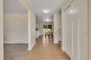 Hall with stairs, light wood-type flooring, and light carpet
