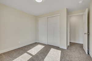 Unfurnished bedroom featuring light carpet and a closet