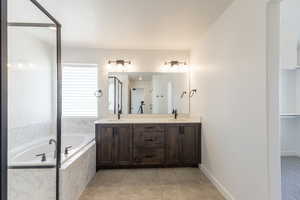 Full bathroom featuring double vanity, a walk in closet, and a garden tub