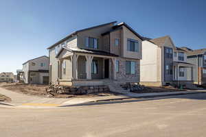 Modern home featuring covered porch, a residential view, and stone siding