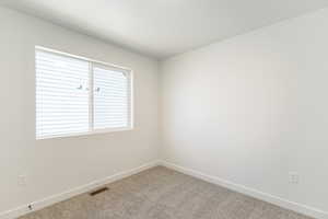 Carpeted spare room featuring baseboards