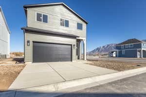 View of front of home featuring an attached garage, a mountain view, and concrete driveway
