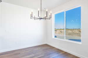 Unfurnished dining area featuring dark wood finished floors and a chandelier