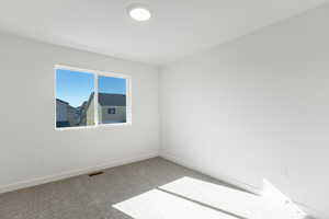 Carpeted spare room featuring baseboards