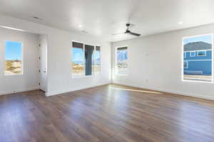 Unfurnished room featuring dark wood-style floors, a ceiling fan, healthy amount of natural light, and a textured ceiling