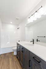 Bathroom featuring vanity, shower / bathtub combination, and dark wood-style flooring