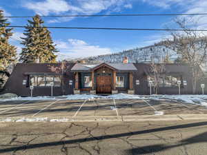 View of front of property with a metal roof, a chimney, and uncovered parking