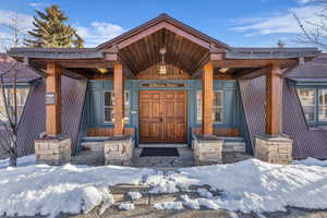 Snow covered property entrance with covered porch