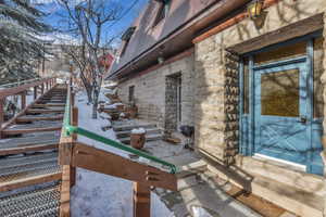 View of snowy exterior featuring stone siding and entry steps