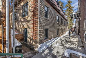 View of side of home featuring stone siding and a gate