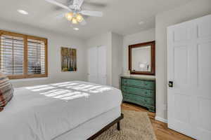 Bedroom with light wood-style floors, ceiling fan, recessed lighting, and a closet