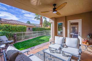 Fenced backyard with a patio, an outdoor hangout area, and a ceiling fan