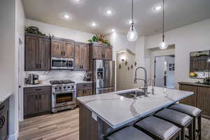 Kitchen with custom cabinetry, stainless steel appliances, pendant lighting over island/kitchen bar, and quartz countertops
