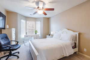 Bedroom with an office area, carpet flooring, and a ceiling fan