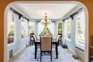Dining room featuring arched walkways, a chandelier, and stone tile flooring