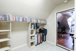 Walk in closet with vaulted ceiling and light carpet