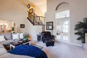 Living room featuring high vaulted ceiling, carpet floors, stairs, french doors, and arched walkways