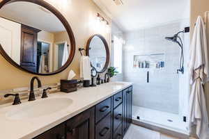 Full bath featuring double vanity and a shower stall